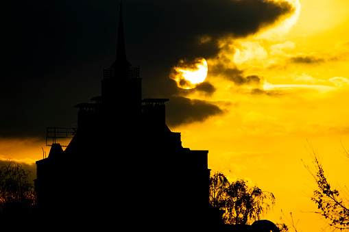 the silhouette of the building against the background of the setting sun behind a cloud. the general plan