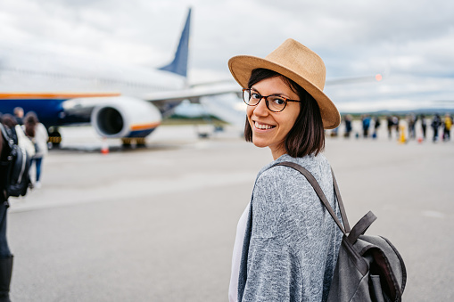 Portrait of a beautiful young woman boarding an airplane for vacation.