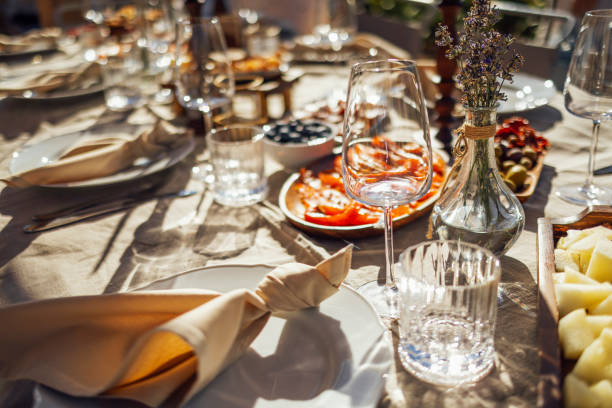 hairs and a table for guests, decorated with candles, are served with cutlery and crockery Wedding. Banquet. Chairs and a table for guests, decorated with candles, are served with cutlery and crockery and covered with beige tablecloth. The table stands on a green summer backyard banquet area dinner party stock pictures, royalty-free photos & images