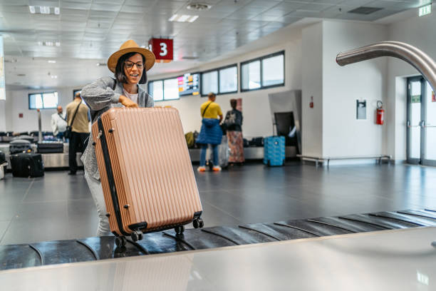 молодая женщина забирает свой багаж из багажной карусели в аэропорту - luggage ramp стоковые фото и изображения