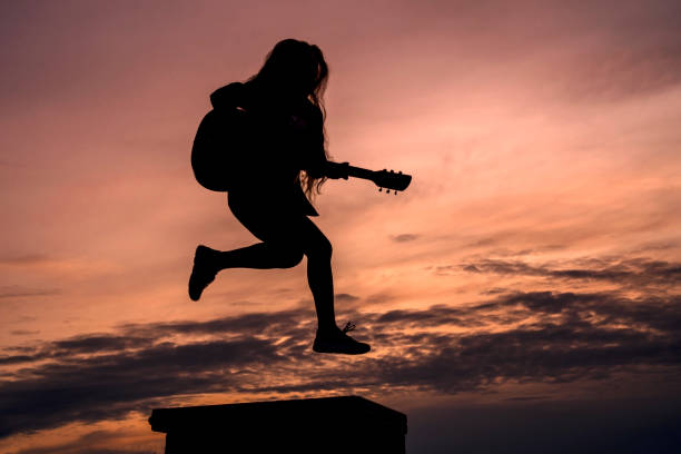 istock Silhouette woman playing guitar in sunset 1457927535