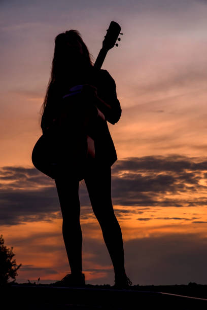 istock Silhouette woman playing guitar in sunset 1457927538