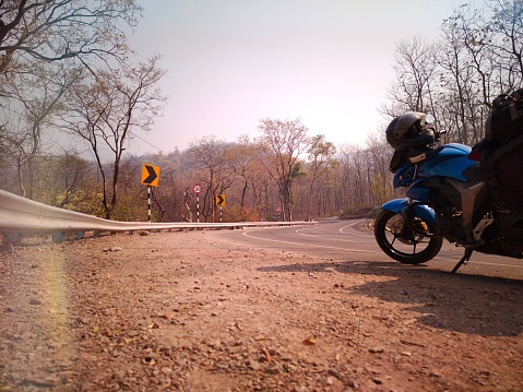 Uttarakhand, India - April 7th, 2021 : Motorbiker travelling, autumn day, motorcycle off road, the driver stands with open arms to the side, to meet a new day, adventurer,