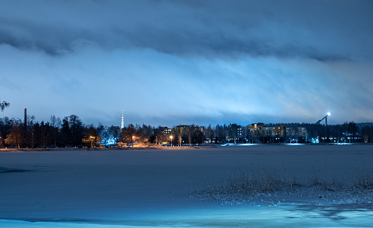 Finland, Lahti urban area. Winter night cityscape illuminated by backlight, the coastal part of the city and the lake in ice.