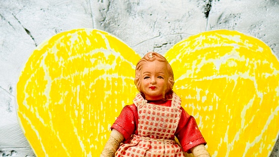 Vintage puppet, blond woman in front of a yellow heart shape background