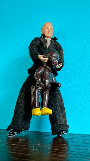 Vintage puppet, black dresse man holding a black baby doll