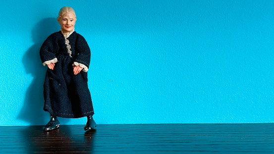 Vintage puppet, grandmother standing on blue background
