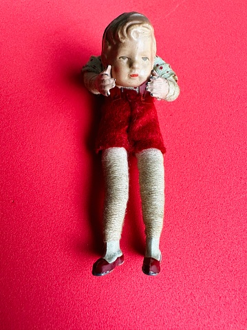 Vintage puppet holding detached head on red background