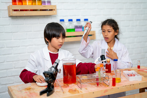 Young boy and girl have fun with science class and using several types of equipment in classroom to get more skill in lab work.