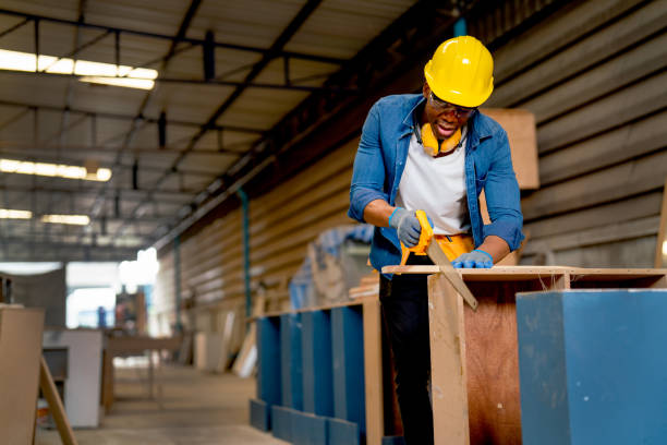 front view of african american carpenter man use sawing wood to work with timber on table during work in factory workplace area. - carpenter carpentry craft skill imagens e fotografias de stock