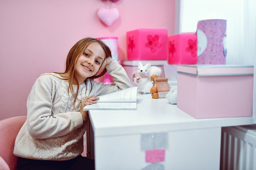Smiling Female Child Studying On Bedroom Desk