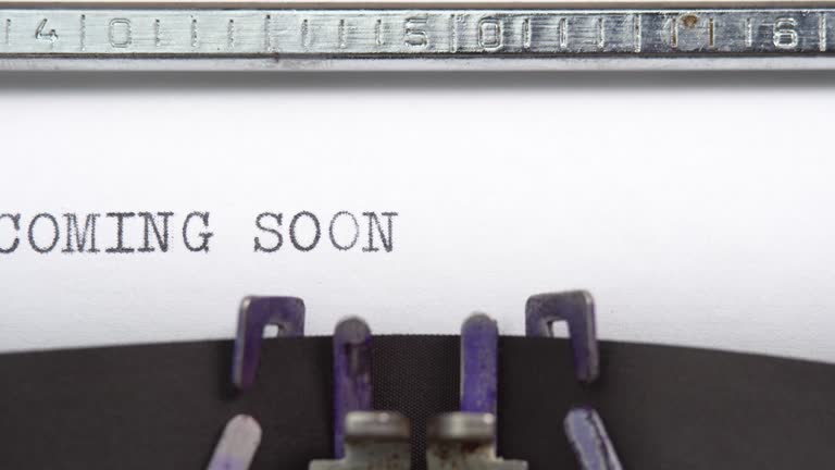 Coming Soon phrase close up being typing and centered on a sheet of paper on old vintage typewriter mechanical