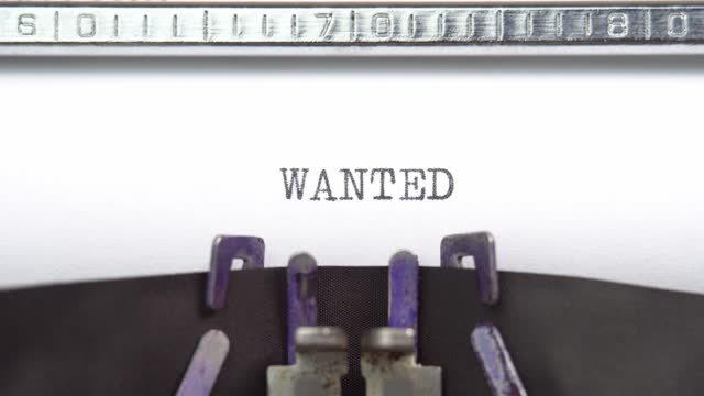 Wanted word closeup being typing and centered on a sheet of paper on old vintage typewriter mechanical
