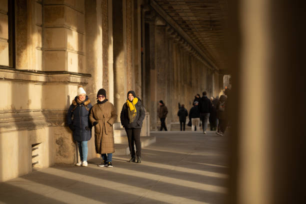 Three tourist ladies walk through a passage in Berlin during a cold winter day