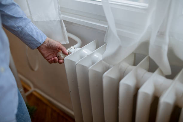 istock Woman Turning on Heat on Radiator 1457946538