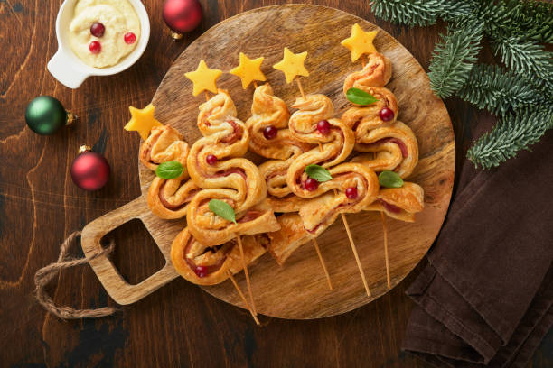 istock Christmas or New Year appetizer. Christmas tree shape puff pastry buns with cheese and ham. Group of Christmas tree shapes on wooden board. Festive idea for Christmas or New Year dinner. Top view. 1457948770