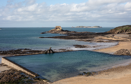 St Malo, Brittany,  France on Jan 7, 2023: famous sea water swimming pool with Petit Bé Fortress in the background
