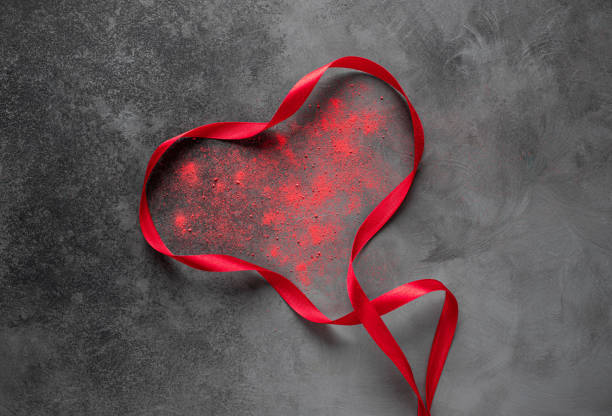 istock Heart shape from red ribbon on dark textured background. 1457951558
