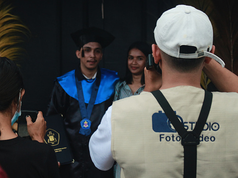 Ambon, Indonesia - October 12, 2022 : a photographer is taking pictures of people graduating