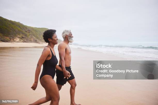 Smiling Mature Couple In Swimsuits Walking Toward The Ocean Stock Photo - Download Image Now