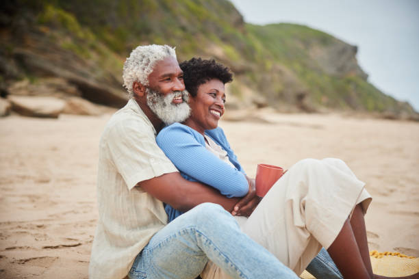 istock Smiling mature couple drinking coffee on a sandy beach 1457953230