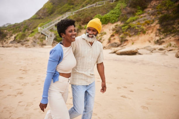 istock Mature couple walking arm in arm on a sandy beach 1457953618