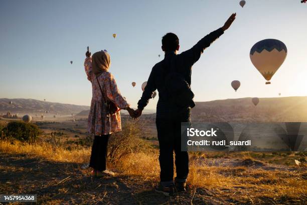 Young Muslim Couple Enjoy The Sunrise With View Of Hot Balloon In Goreme Stock Photo - Download Image Now