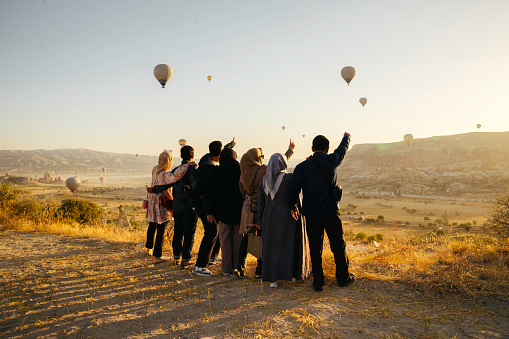 group of people enjoy the sunrise with view of  hot balloon in goreme