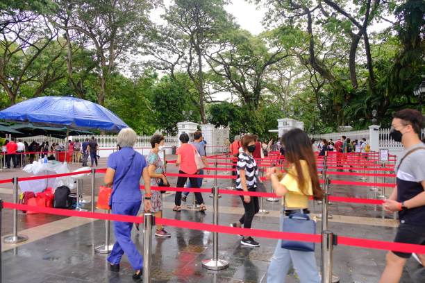 persone che camminano a passo svelto sotto la pioggia per unirsi alla fila per visitare l'istana, durante l'open house. al pubblico è consentito l'accesso durante il capodanno cinese. messa a fuoco selettiva. - military uniform barricade boundary police uniform foto e immagini stock