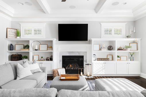 A living room's built-in shelving with a fireplace, television, and decorations.