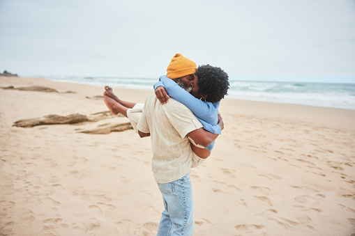 Mature man kissing his wife in his arms while enjoying a day together on a sandy beach