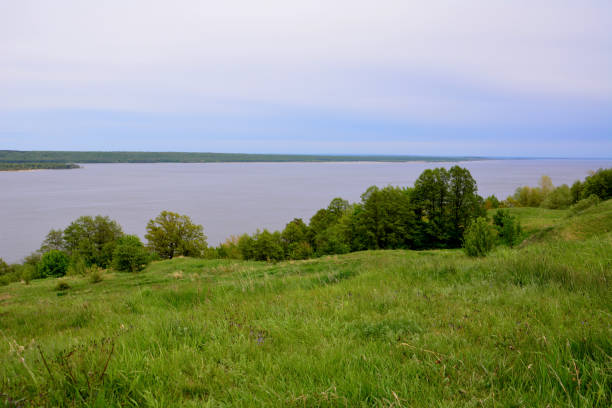istock green rolling hill with green trees and Volga river and rainy sky on background 1457956977