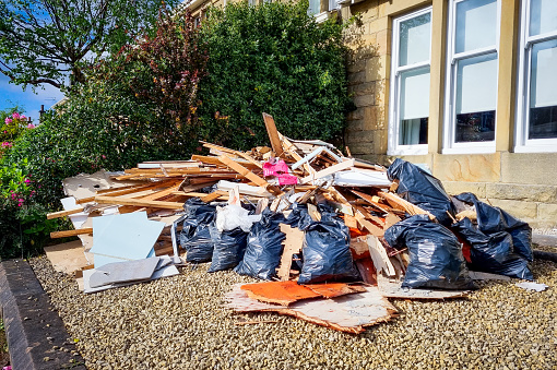 Timber and rubbish bags full of waste, waiting for refuse collection on a residential British street.