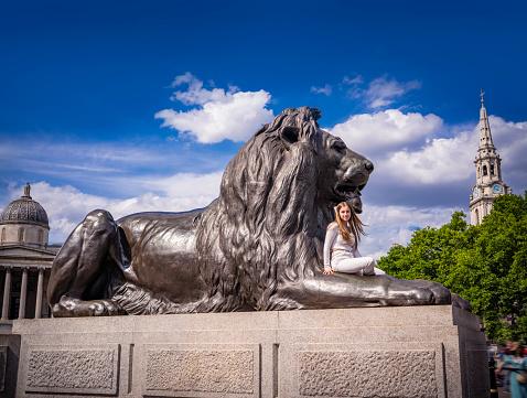 London blond young tourist woman in Trafalgar Square Lion UK United Kingdom, Great Britain England