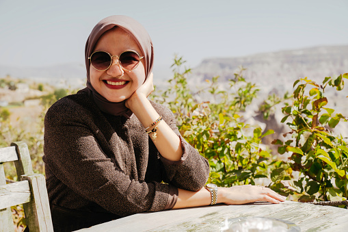 asian muslim woman siting in cafe outdoor seeing the goreme park