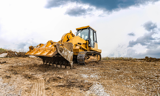 Track bulldozer, earth-moving equipment at a construction site on dull day. Land clearing, grading, ground excavation of large job of new residential building. Construction of heavy equipment for earthwork