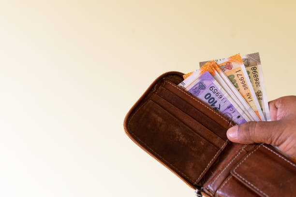 Man holding a wallet full of cash or indian rupees notes.