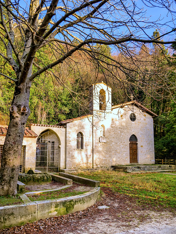 The small church of the ancient hermitage of Santo Marzio (Saint Martius), among the wooded mountains of Gualdo Tadino, a medieval village between Spoleto and Gubbio in the Italian region of Umbria. The Hermitage was built around 1219 by the first Franciscans who arrived in these mountains, becoming a place of penance and prayer. According to official sources, this hermitage was visited by St. Francis of Assisi in 1224. The Umbria region, considered the green lung of Italy for its wooded mountains, is characterized by a perfect integration between nature and the presence of man, in a context of environmental sustainability and healthy life. In addition to its immense artistic and historical heritage, Umbria is famous for its food and wine production and for the quality of the olive oil produced in these lands. Wide angle image in high definition format.