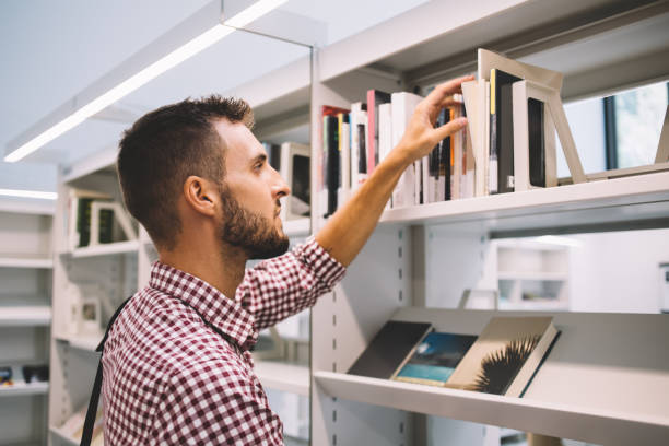 istock Serious male buying book in bookstore 1457973122