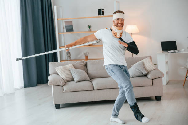 istock Dancing with crutches. Man is at home indoors. Having injuries 1457975608