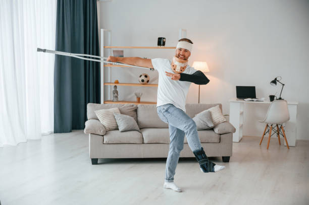istock Positive man with crutches is at home indoors dancing, having fun. Having injuries 1457975676