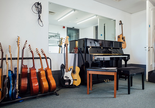 A music classroom filled with a piano and guitars in a secondary school in the North East of England. There is no people.