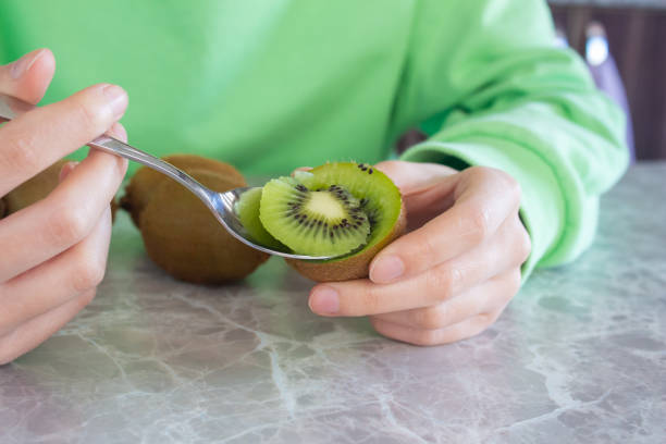 istock Woman eating kiwi fruit 1457977774