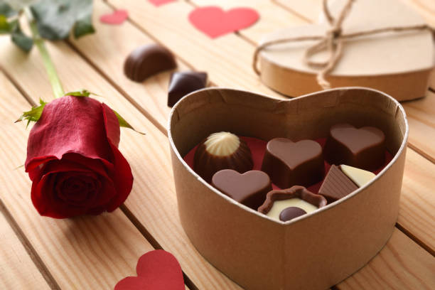 istock Gift box with assorted chocolates on wooden table with rose 1457977929