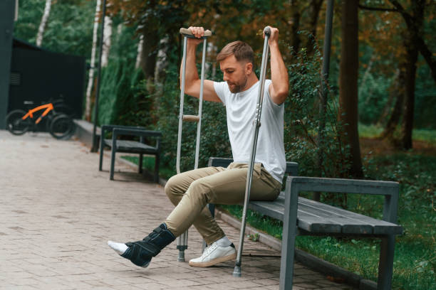 istock Man with crutches is in the park outdoors. Having leg injury 1457978177