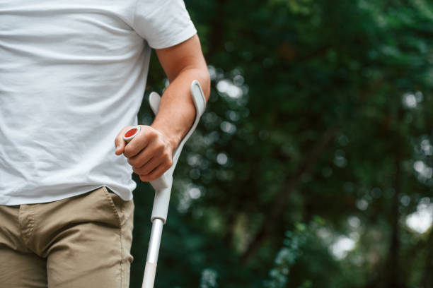 vista ravvicinata. l'uomo con le stampelle è nel parco all'aperto. avere lesioni alle gambe - misalignment foto e immagini stock