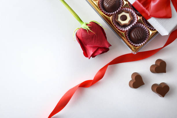 istock Background with box of chocolates and rose on white table 1457978953