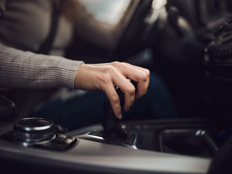 Close up of unrecognizable woman holding her hand on automatic gearshift while driving a car. Photographed in medium format.
