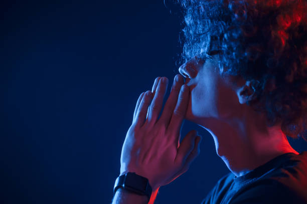istock Side view. Young man with curly hair is indoors illuminated by neon lighting 1457979395