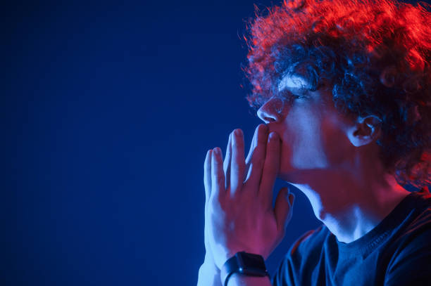 istock Side view. Young man with curly hair is indoors illuminated by neon lighting 1457979422